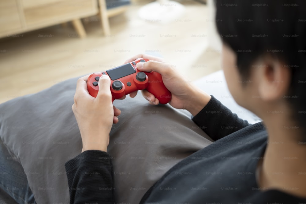 Junger Mann spielt Videospiele auf dem Sofa.