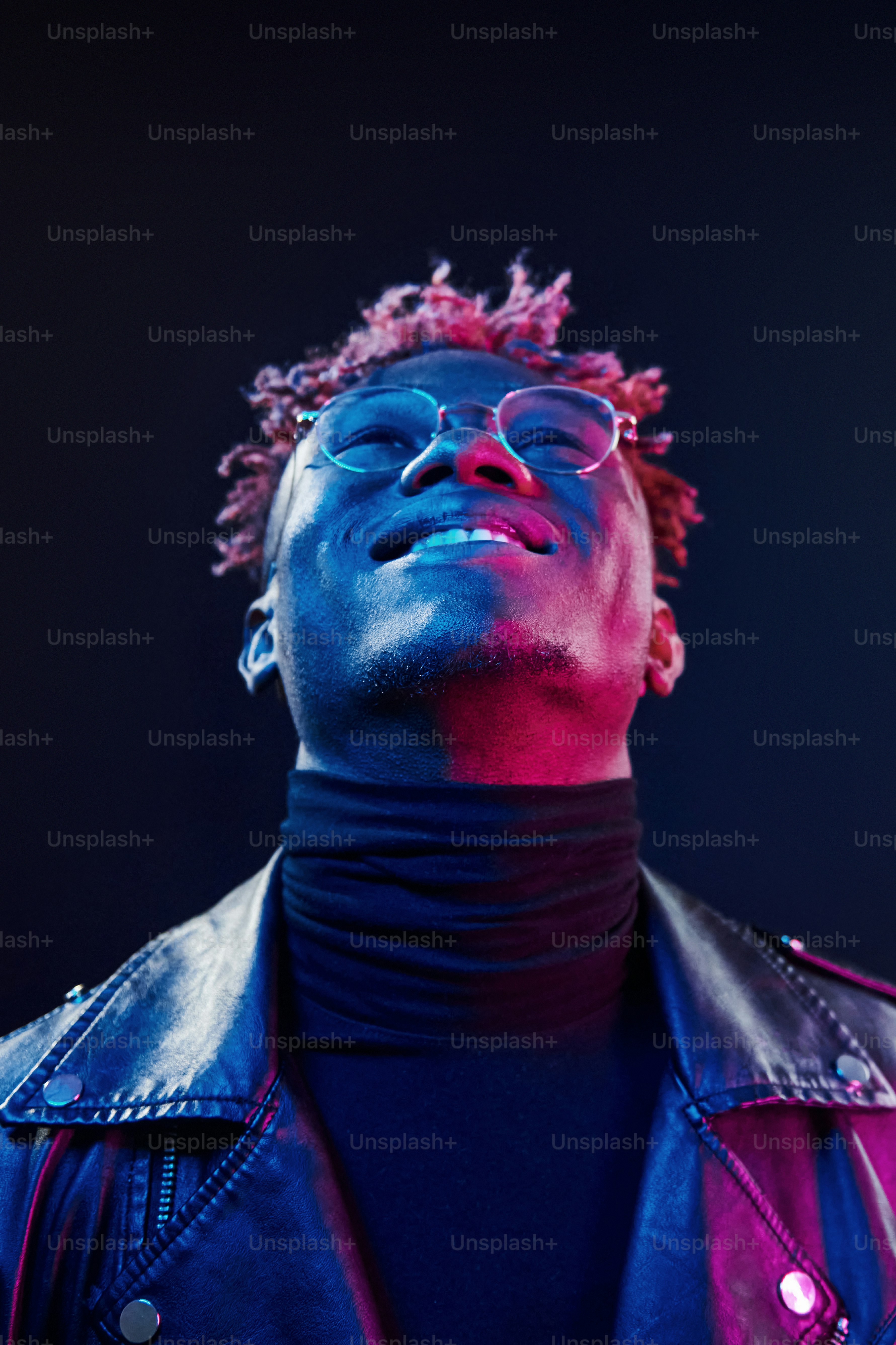 In glasses. Futuristic neon lighting. Young african american man in the studio.