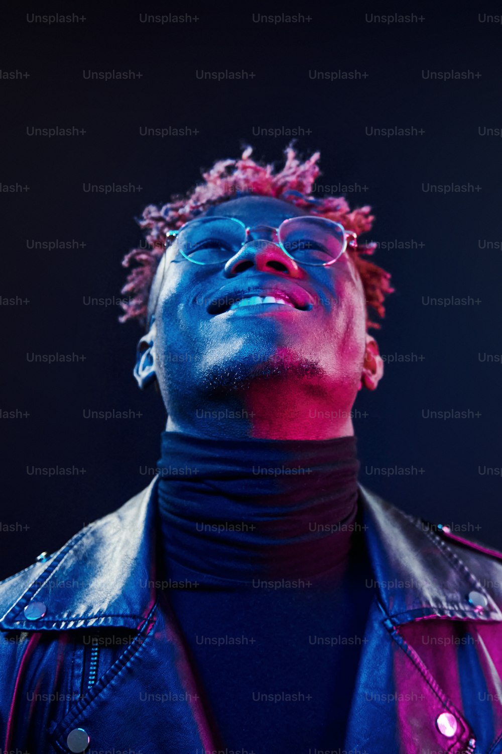 En gafas. Iluminación de neón futurista. Joven afroamericano en el estudio.