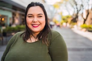 Portrait of young plus size woman smiling while standing outdoors at the street. Urban concept.