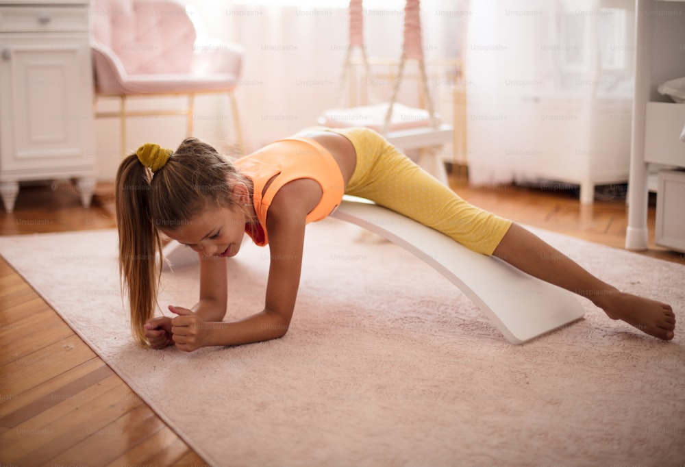 집에서 침실에서 운동을 하는 어린 소녀.