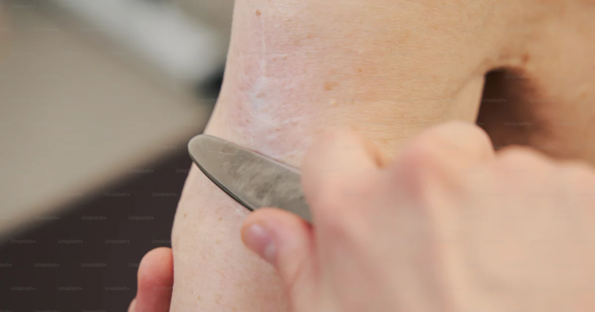 Therapist holding stainless steel scraping instrument and running it ...