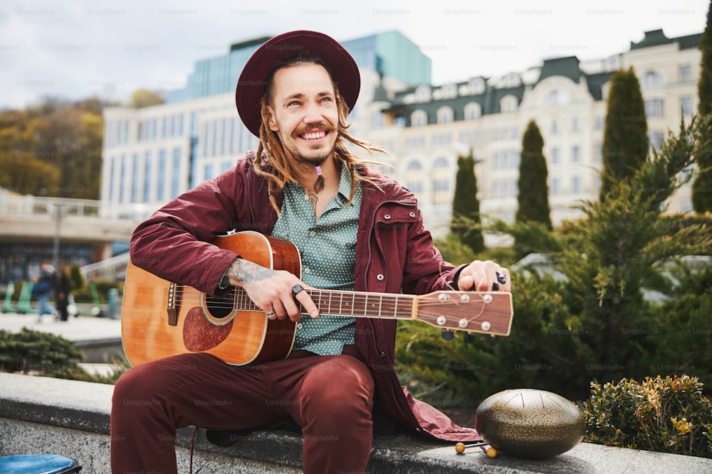 Glückliche männliche Person, die den Blick auf die Stadt genießt, während sie gute Musik auf der Straße spielt