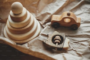 유아를 위한 친환경 플라스틱 무료 장난감. 반지, 치발기 고슴도치, 자동차 장난감이 나무 테이블에 공예 종이에 있는 현대 천연 나무 피라미드. 어린이를위한 세련 된 간단한 나무 장난감