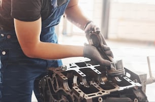 Professional repairman works with broken automobile engine.