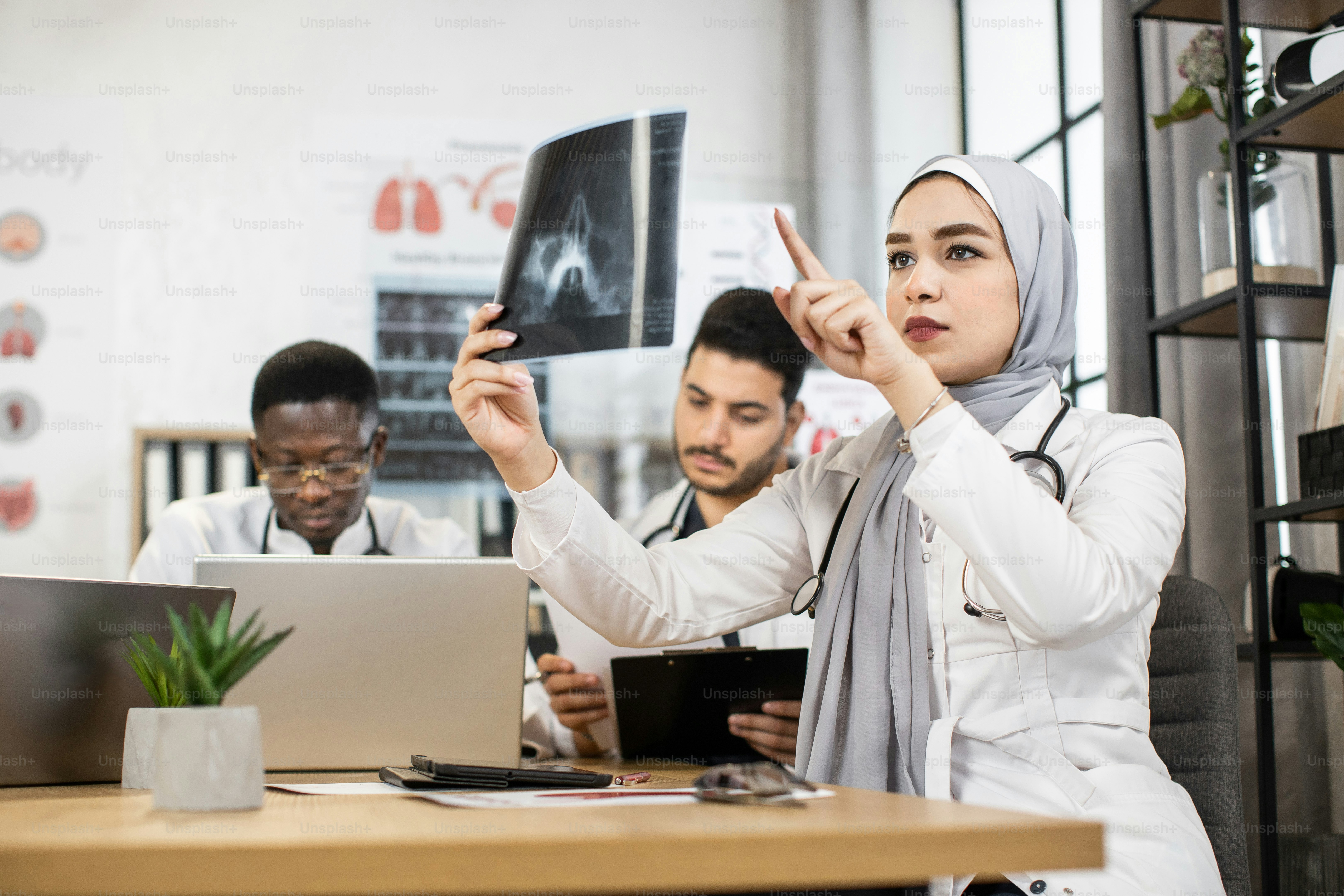 Group of four multiracial doctors using modern gadgets while examining ...