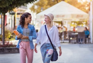 Two women on the street carrying books.