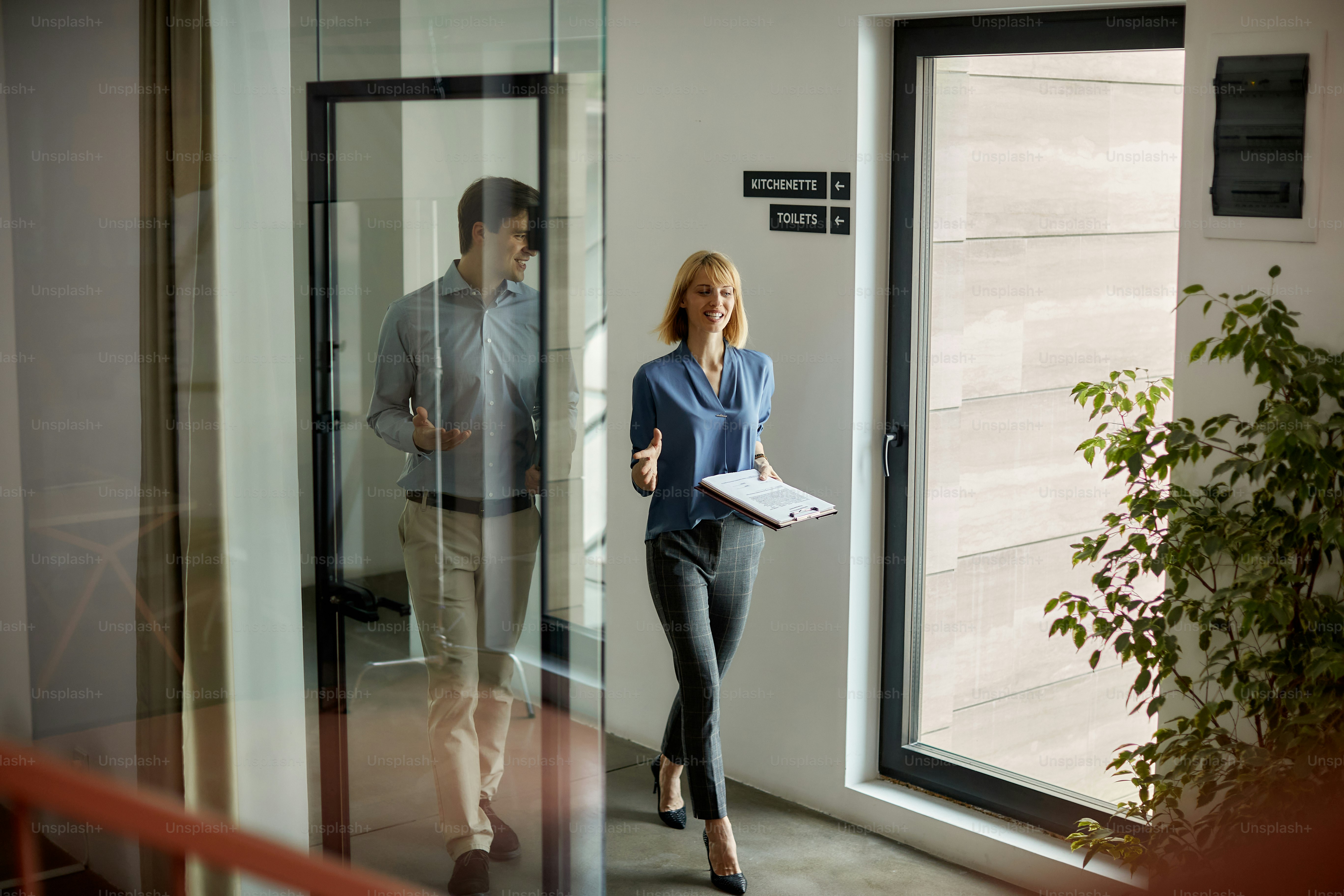 Happy entrepreneurs communicating while walking through the lobby. Focus is on businesswoman.