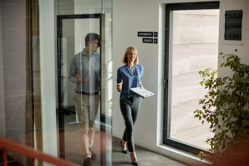 Empresarios felices que se comunican mientras caminan por el vestíbulo. La atención se centra en la mujer de negocios.