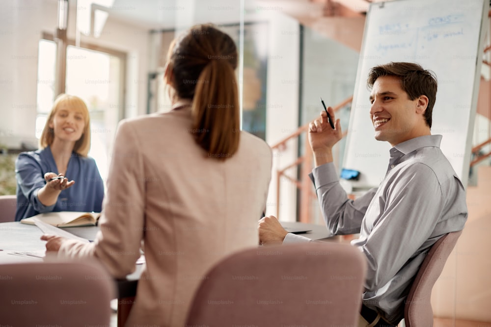 Happy businessman talking with female colleagues while having a meeting in the office.
