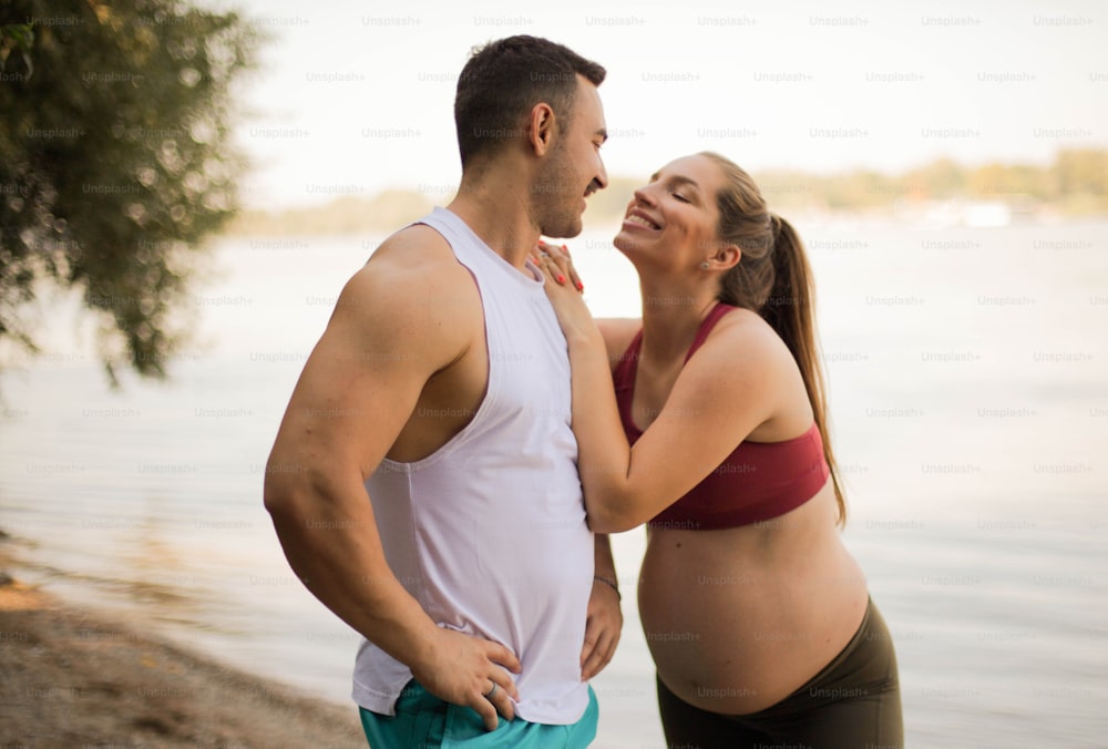 Smiling man and pregnant woman on the beach.