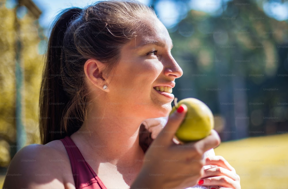 Woman in the park eating apple.