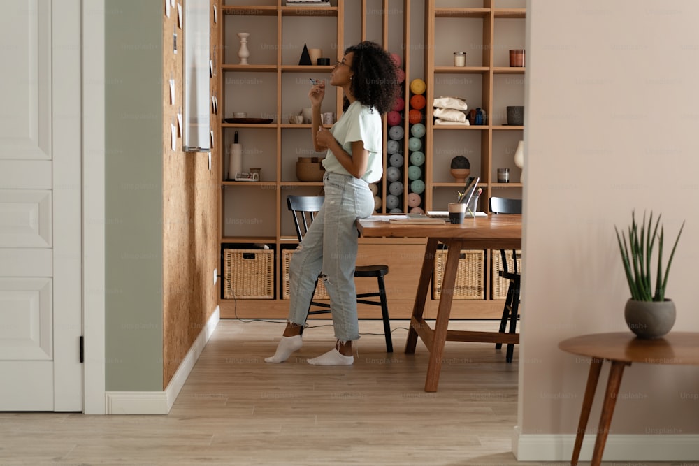 Focused young millennial african american woman in a casual clothes writes on the flip chart in the office. Woman notes aims and goals on white board