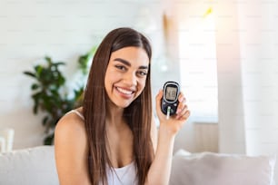 Blood sugar testing at home. Checking Blood Sugar Level At Home. Diabetic Checking Blood Sugar Levels. Woman checking blood sugar level by glucometer and test stripe at home