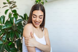 Mujer señalando su brazo con un vendaje después de recibir la vacuna contra el covid-19. Joven mostrando su hombro después de recibir la vacuna contra el coronavirus