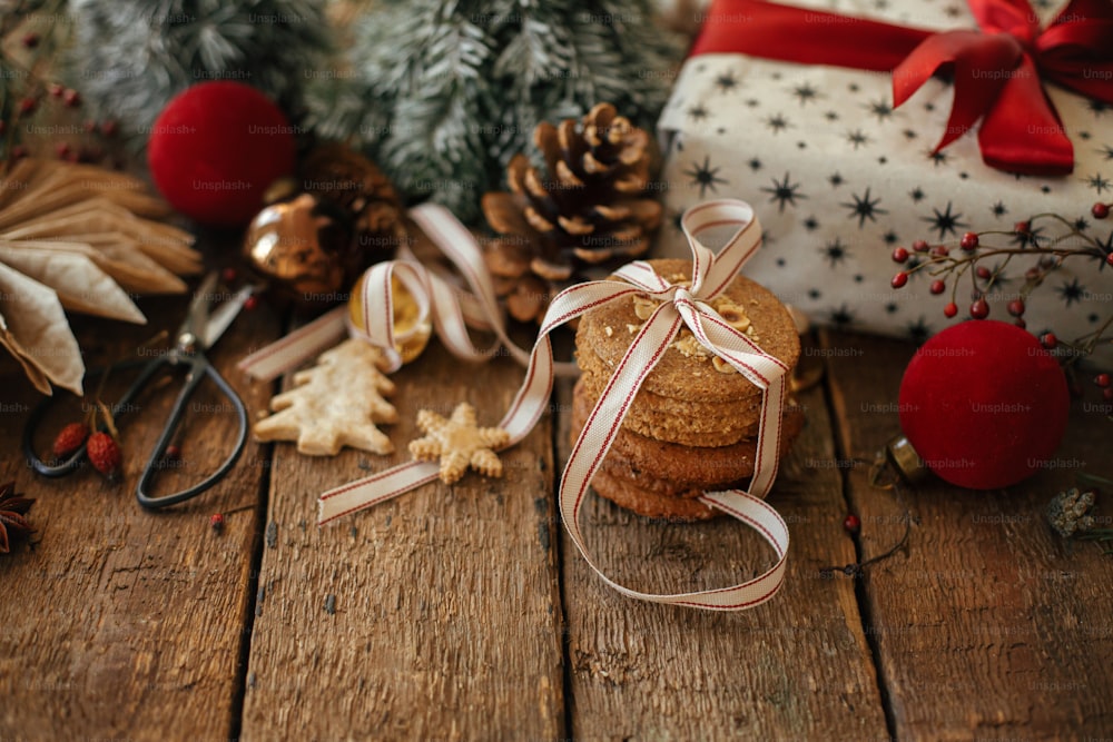 크리스마스 쿠키, 세련된 선물, 소박한 나무 테이블에 축제 장식. 텍스트를 위한 공간이 있는 분위기 있는 크리스마스 구성. 크리스마스 선물, 건강한 오트밀 쿠키, 장식품. 즐거운 휴일 보내세요