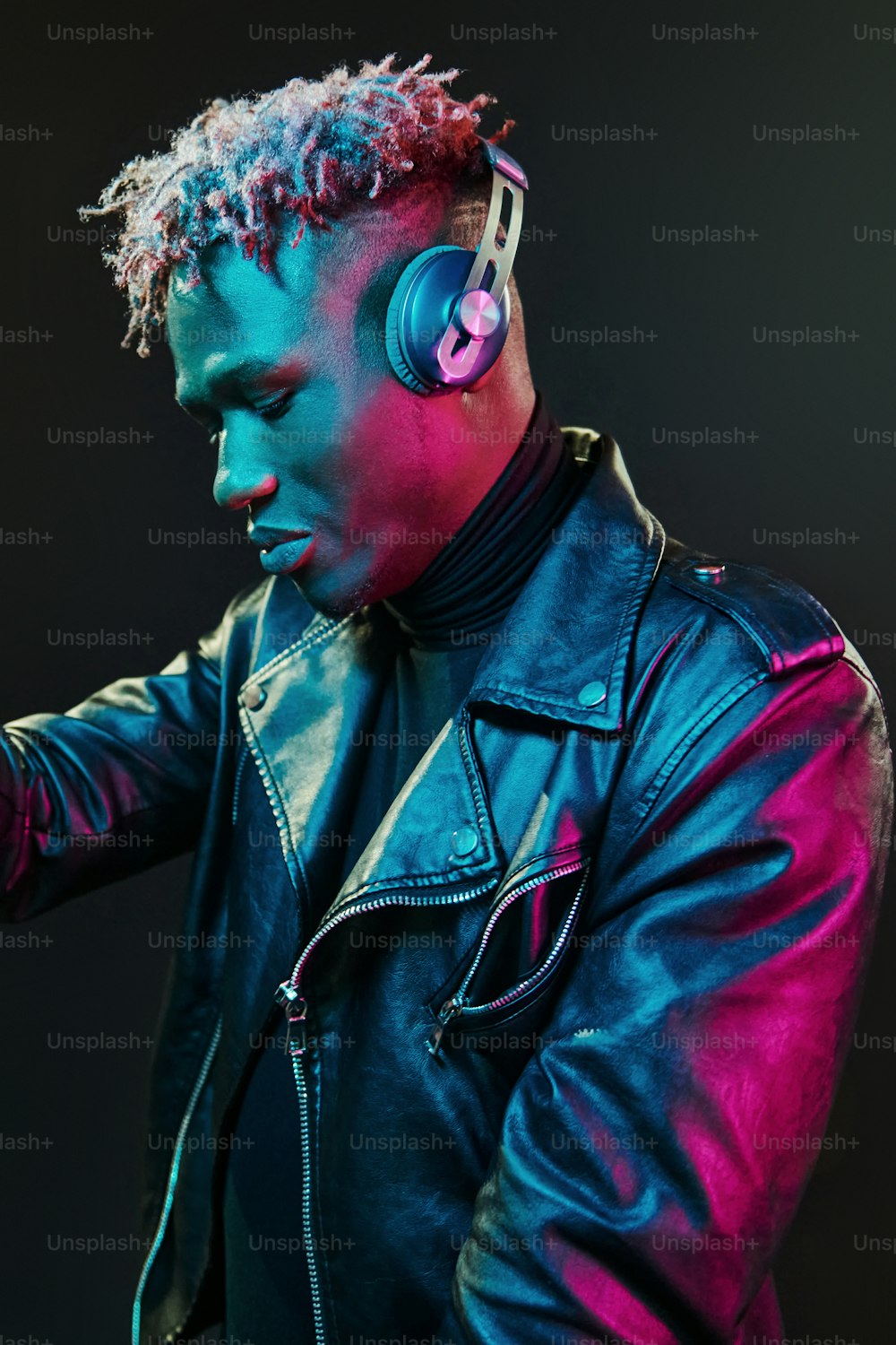 Dancing with headphones on. Futuristic neon lighting. Young african american man in the studio.