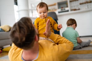 Unhappy little boy feeling jealous while parent spending time with other children at home