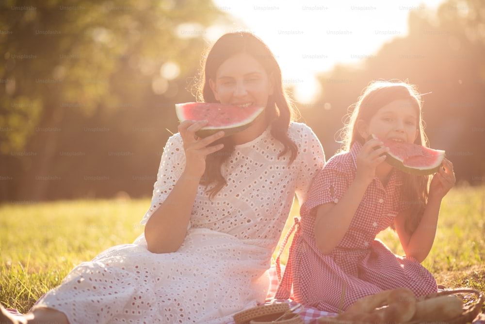 Mother and daughter eating watermelon in nature. Portrait of mother daughter.