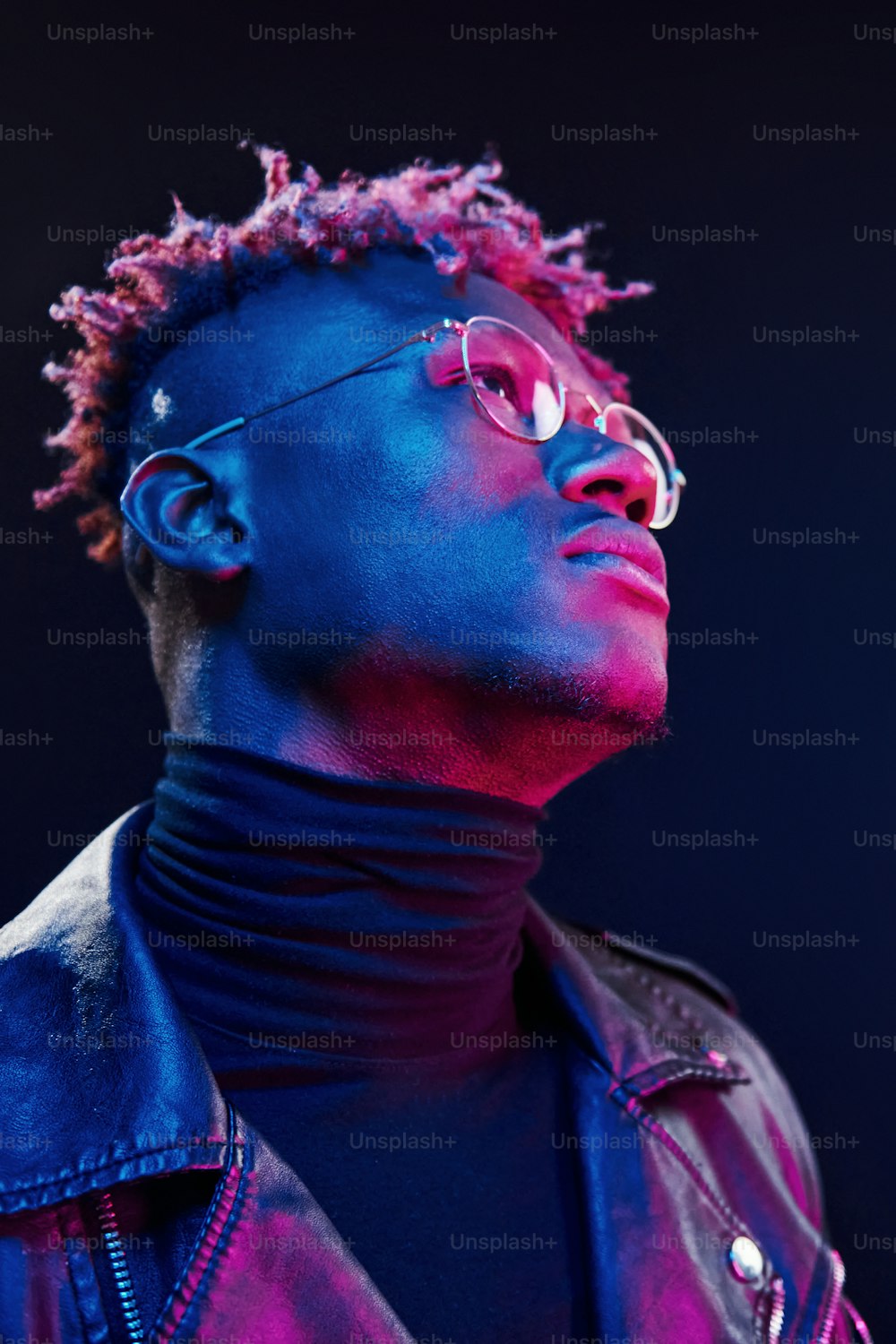In glasses. Futuristic neon lighting. Young african american man in the studio.