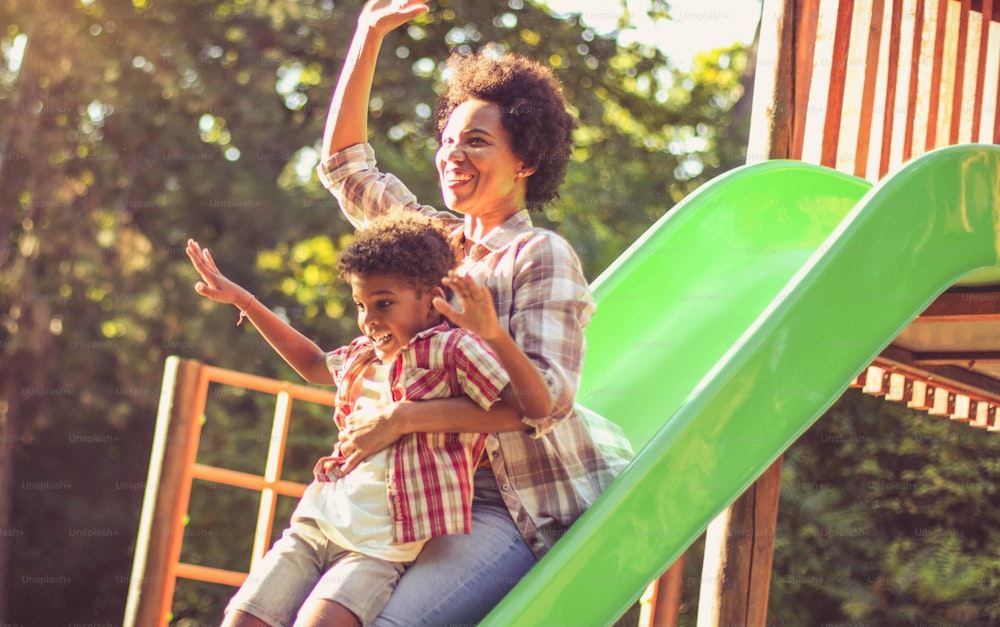 African American mom playing with child on playground.