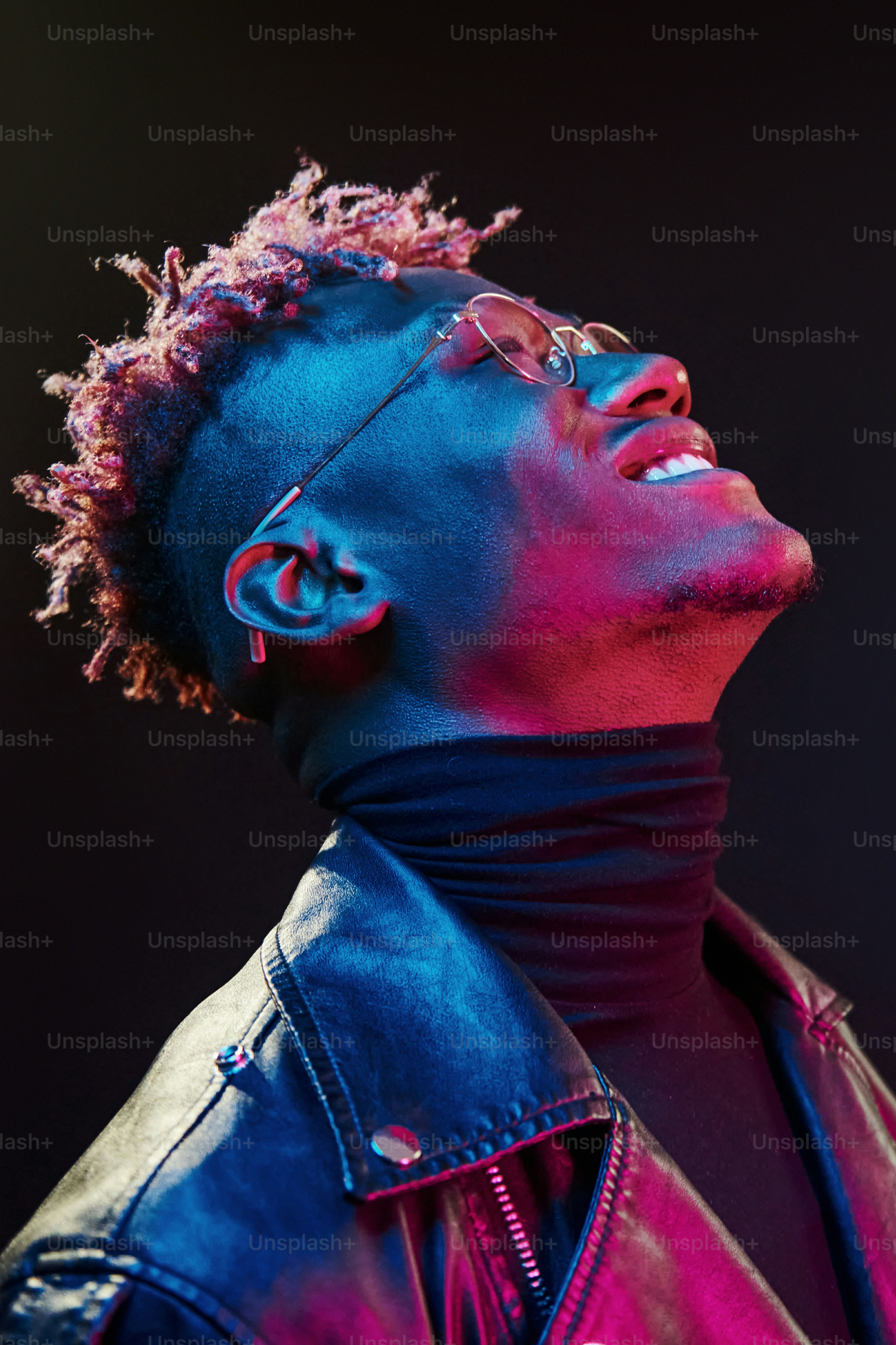 In glasses. Futuristic neon lighting. Young african american man in the studio.
