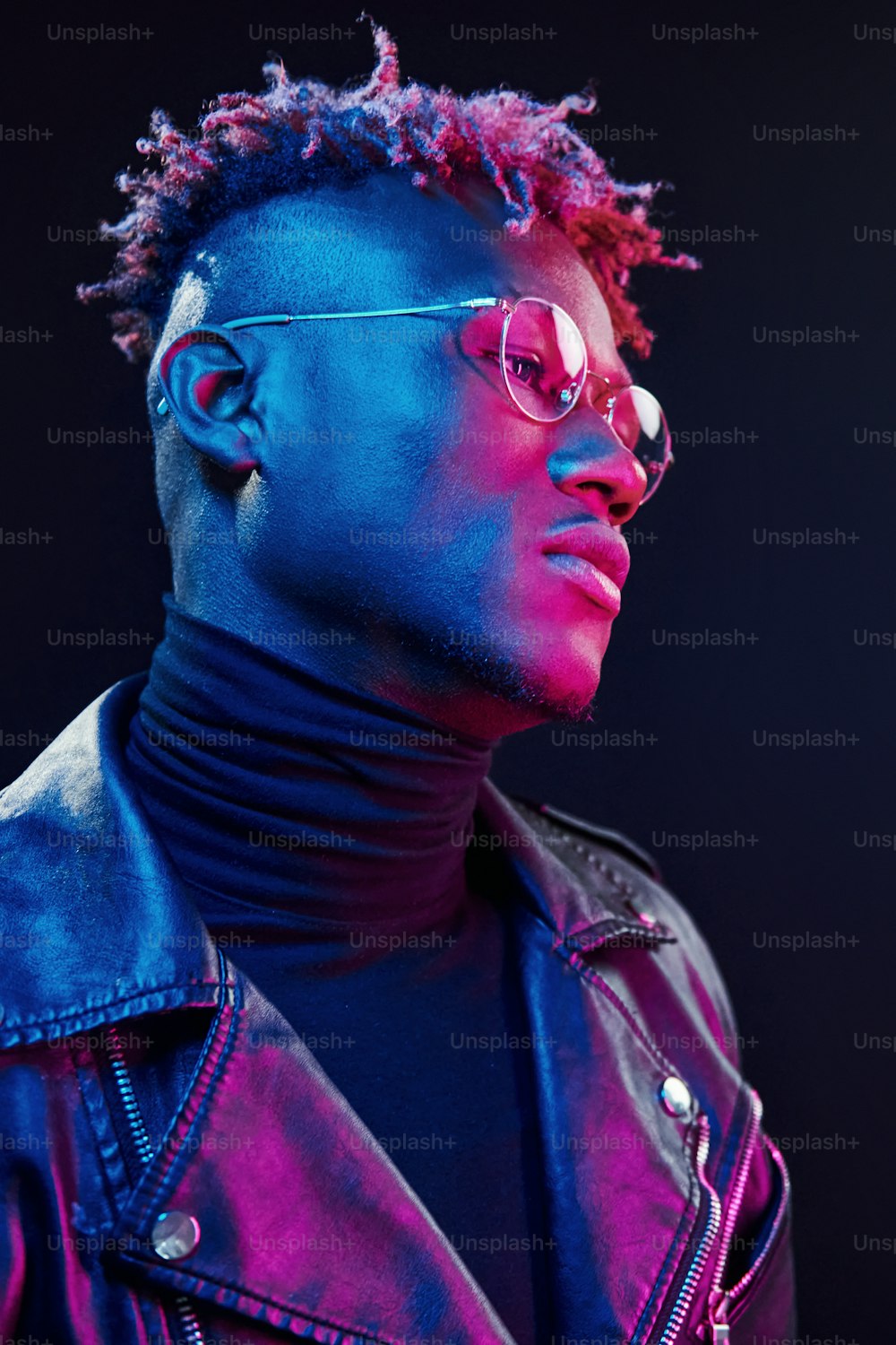 In glasses. Futuristic neon lighting. Young african american man in the studio.