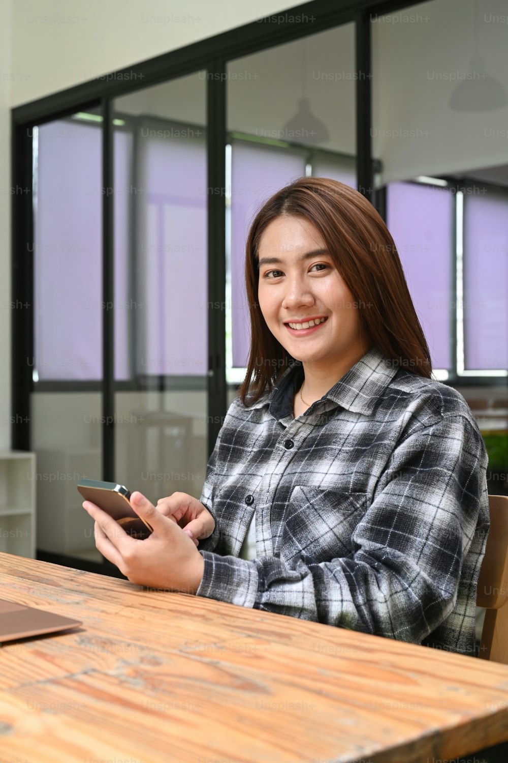 Portrait of cheerful woman holding mobile phone and smiling to camera.