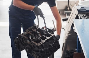 Professional repairman works with broken automobile engine.