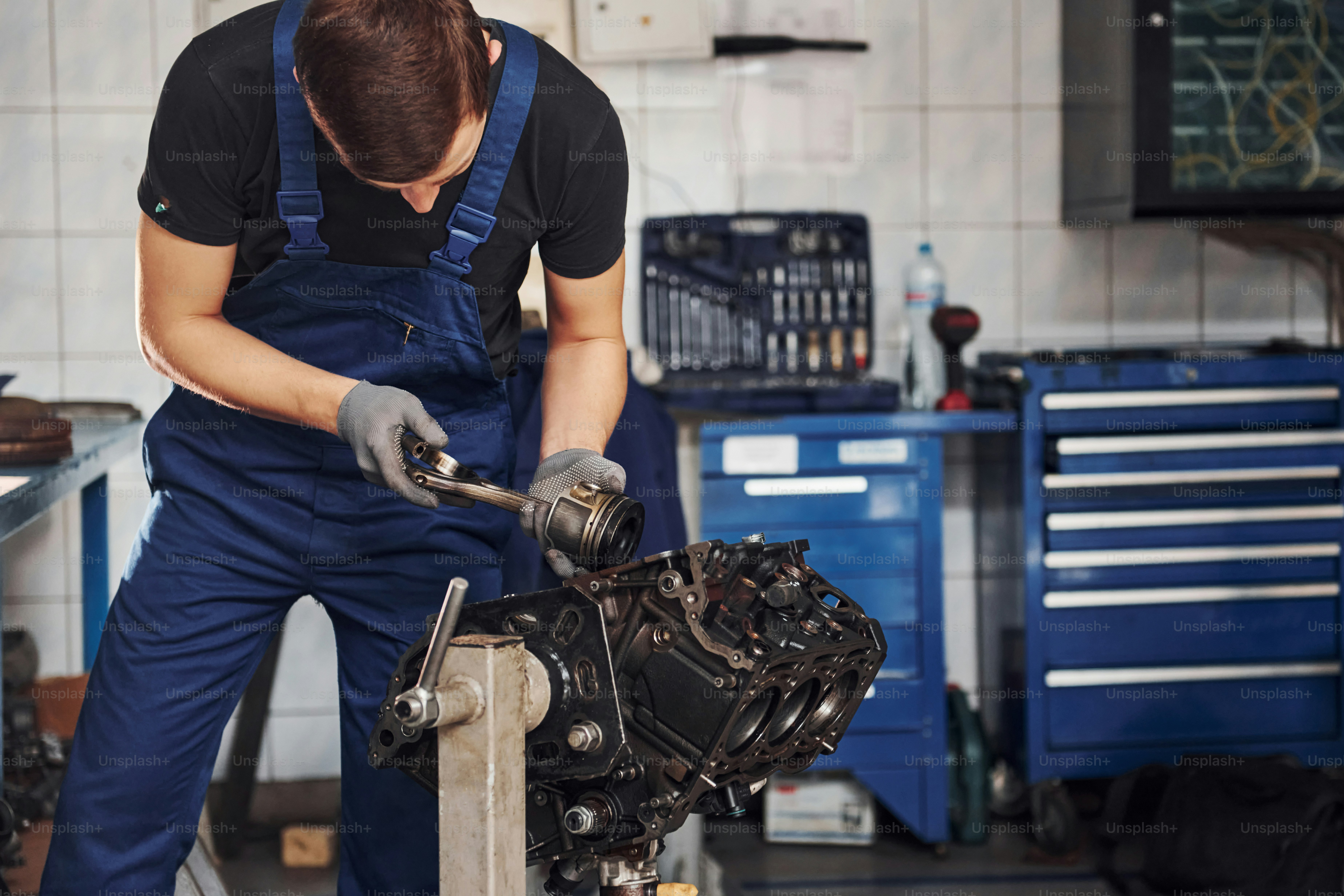 Professioneller Reparaturarbeiter in der Garage arbeitet mit kaputtem Automotor.