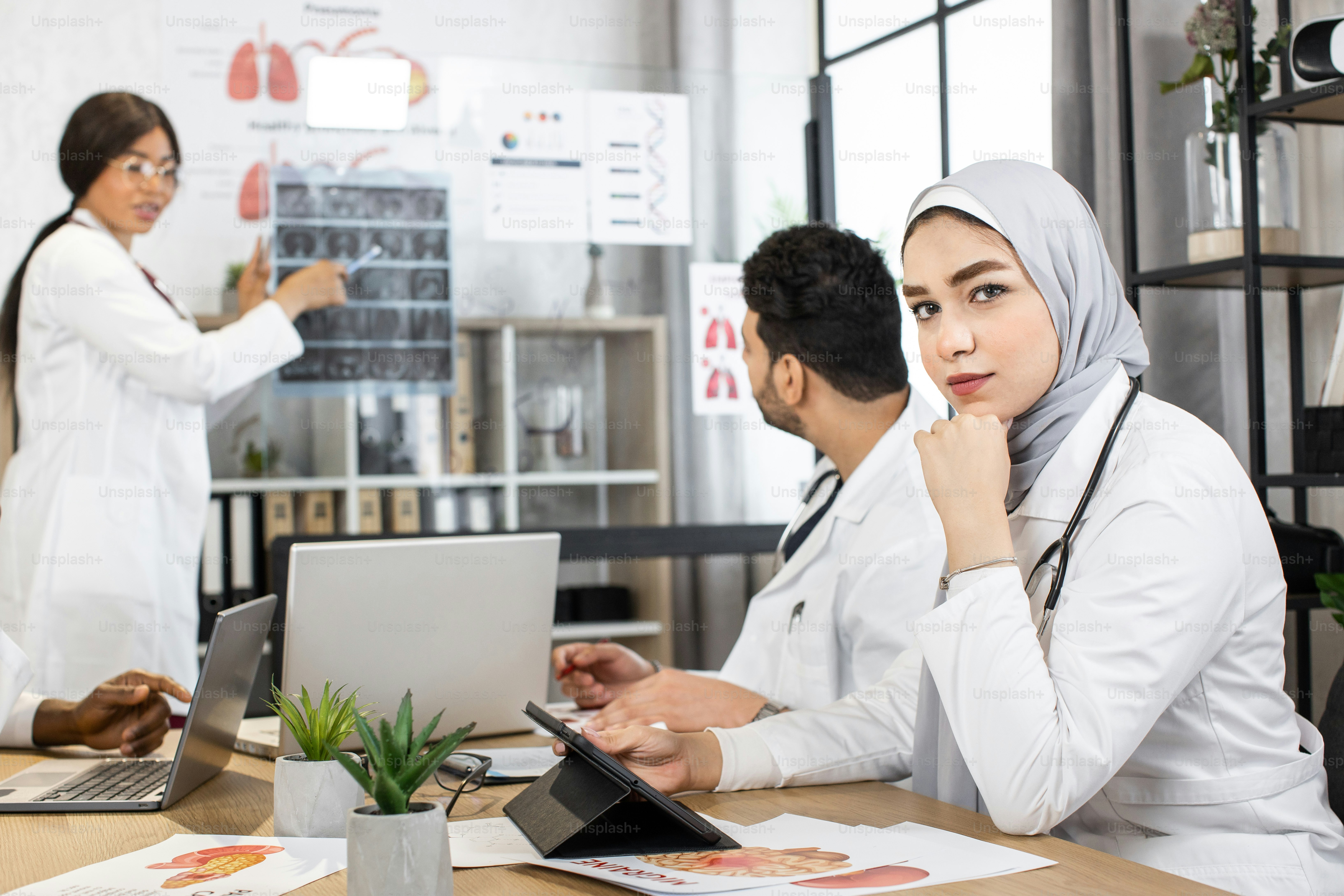 Group of four multiracial doctors using modern gadgets while examining ...