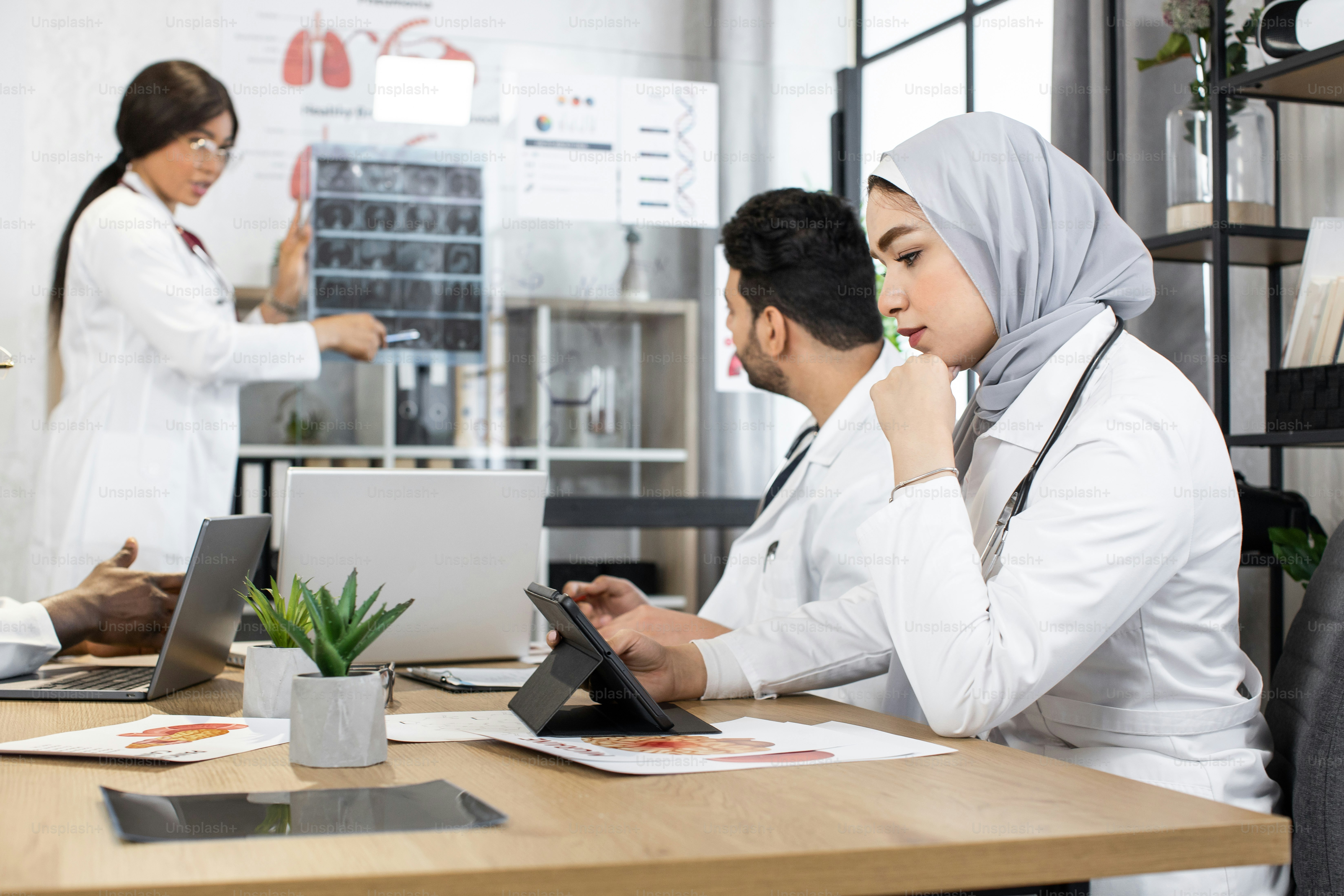 Group of four multiracial doctors using modern gadgets while examining ...