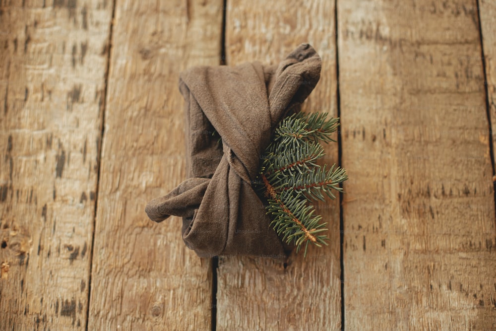 Presente de Natal elegante embrulhado em tecido com ramo de abeto na vista rústica de madeira do tampo da mesa. Zero desperdício de férias de inverno e presente. Furoshiki eco friendly presente. Boas festas e Feliz Natal