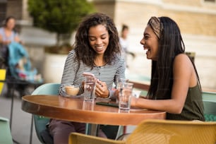 Two women in café using smart phone.