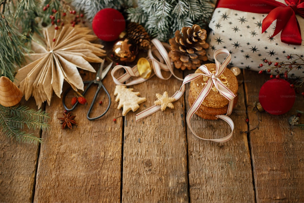 メリークリスマス！素朴な木製のテーブルにクリスマスクッキーとお祝いの装飾。オートミールクッキーとクリスマスプレゼントを添えた雰囲気のあるスタイリッシュなクリスマスコンポジション。テキスト用のスペース。楽しい休暇をお過ごしください