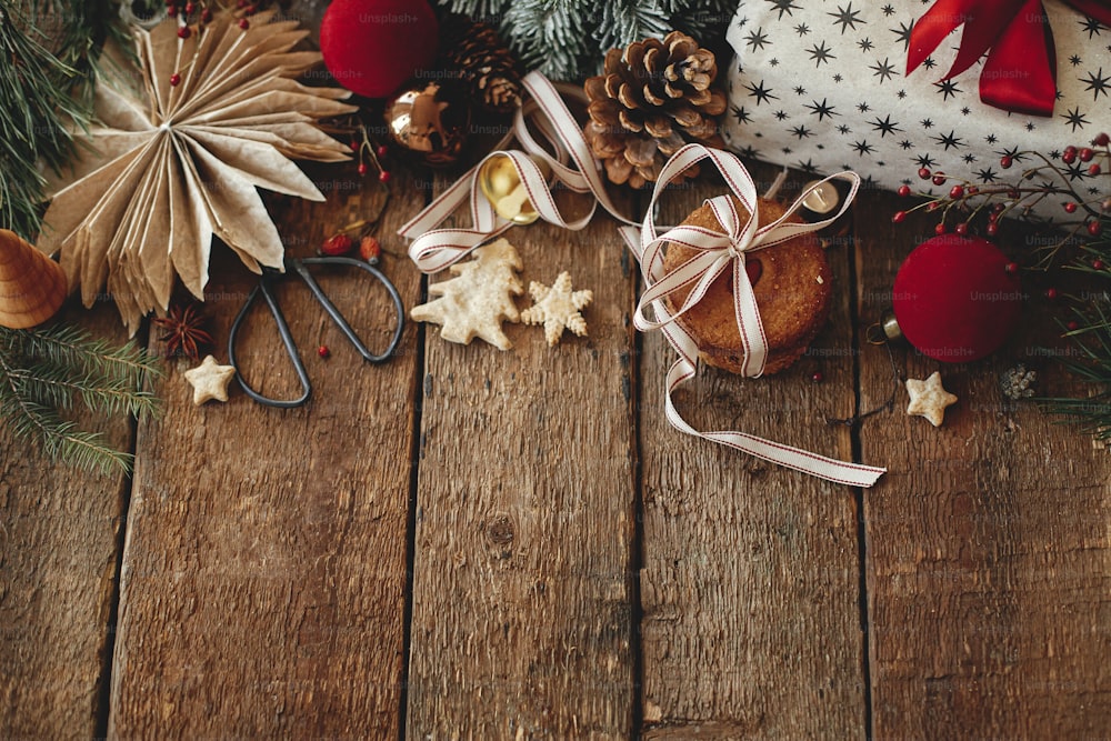 분위기 있는 세련된 크리스마스 구성, 텍스트를 위한 공간이 있는 플랫 누워. 크리스마스 쿠키, 세련된 선물, 소박한 나무 테이블에 축제 장식. 크리스마스 선물, 건강한 오트밀 쿠키, 장식품