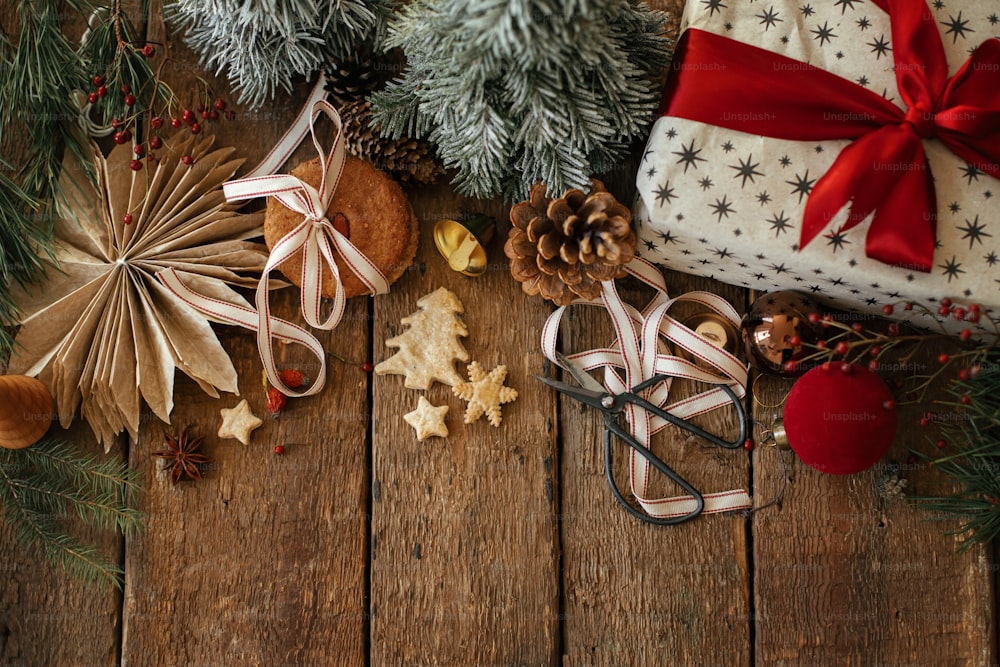 クリスマスクッキー、スタイリッシュなギフト、素朴な木製のテーブルの上のお祝いの装飾。雰囲気のあるスタイリッシュなクリスマスの構図、テキスト用のスペースを備えたフラットレイ。クリスマスプレゼント、ヘルシーなオートミールクッキー、オーナメント