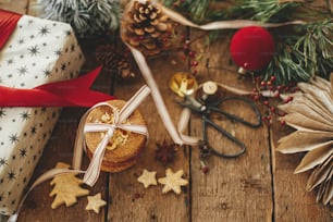 クリスマスクッキー、ギフト、素朴な木製のテーブルの上のお祝いの装飾。雰囲気のあるスタイリッシュなクリスマスの構図。クリスマスプレゼント、ヘルシーなオートミールクッキー、オーナメント。休日の不機嫌な画像。メリークリスマス