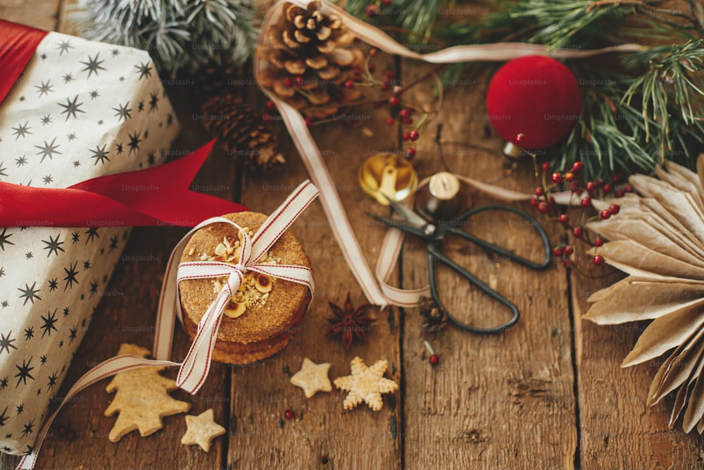 Galletas navideñas, regalo, decoraciones festivas en mesa de madera rústica. Composición navideña atmosférica y elegante. Regalo de Navidad, galletas de avena saludables, adornos. Imagen malhumorada de vacaciones. Feliz Navidad