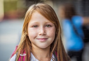 カメラに向かって微笑む赤い髪の陽気な女の子の肖像画。フォーカスは前景にあります。