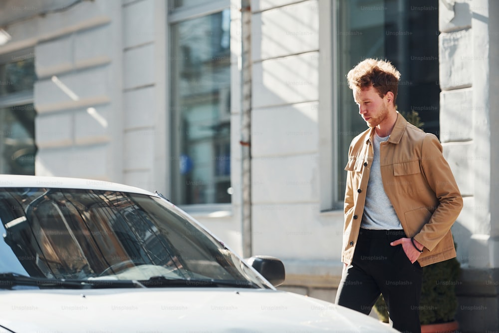 Walks to his car. Elegant young man in formal classy clothes outdoors in the city.