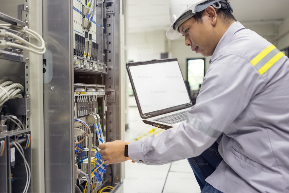 Network administrator holding laptop in hand working Configuration with core switch on rack cabinet in data center