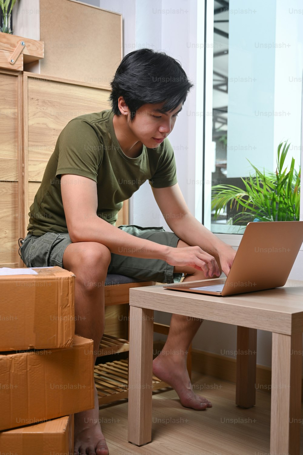 Start up small business owner sitting with cardboard box and working with laptop at home.