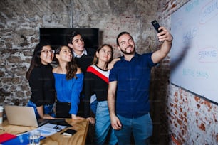 Young hispanic business people having fun taking a selfie at work in Mexico