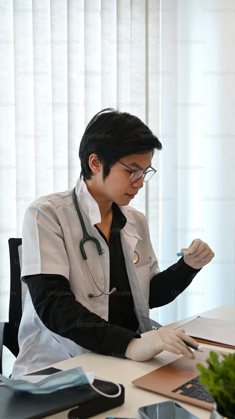 Porträt eines gutaussehenden Arztes, der im Krankenhaus mit einem Laptop arbeitet.