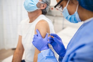 Arzt trägt PSA-Anzug und OP-Maske und verwendet Impfstoff mit infiziertem Patienten im Quarantäneraum Covid-19-Coronavirus-Ausbruch oder Covid-19, Konzept der Covid-19-Quarantäne