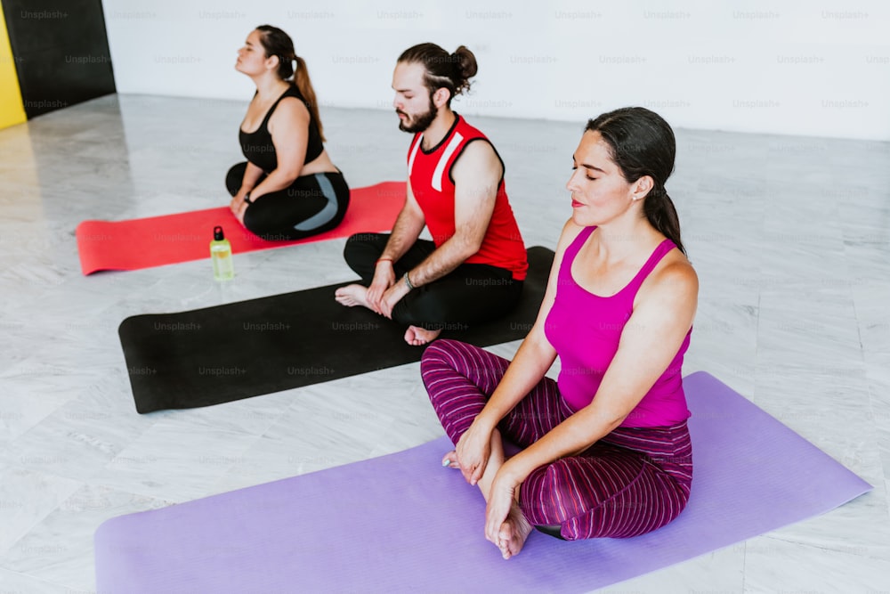 Grupo de jóvenes latinos meditando tranquilamente en un estudio de yoga en América Latina