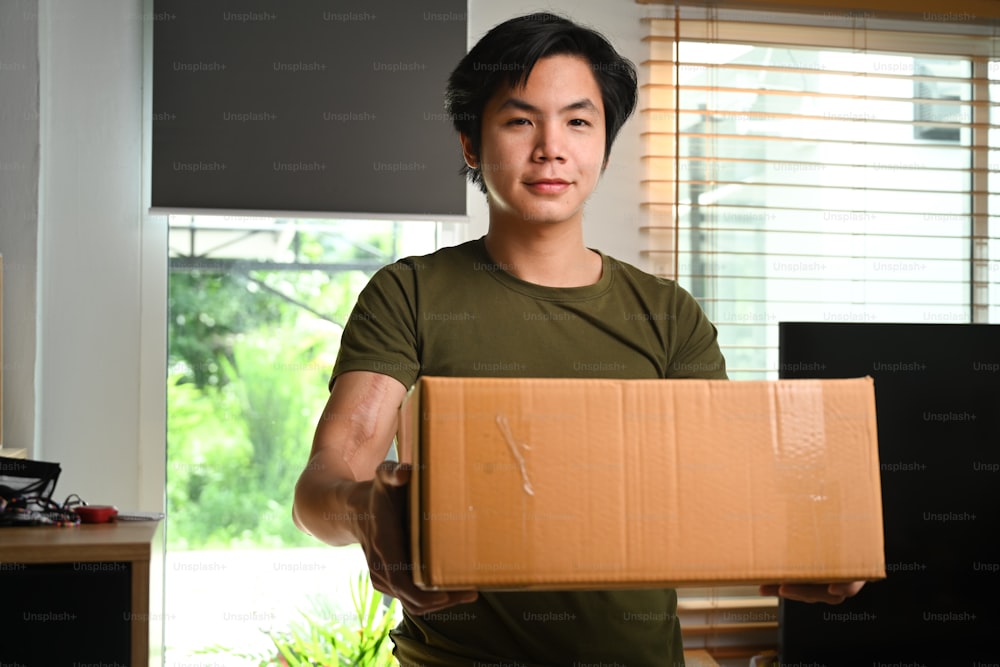 Start up small business owner holding cardboard box "npreparing sending to customers.