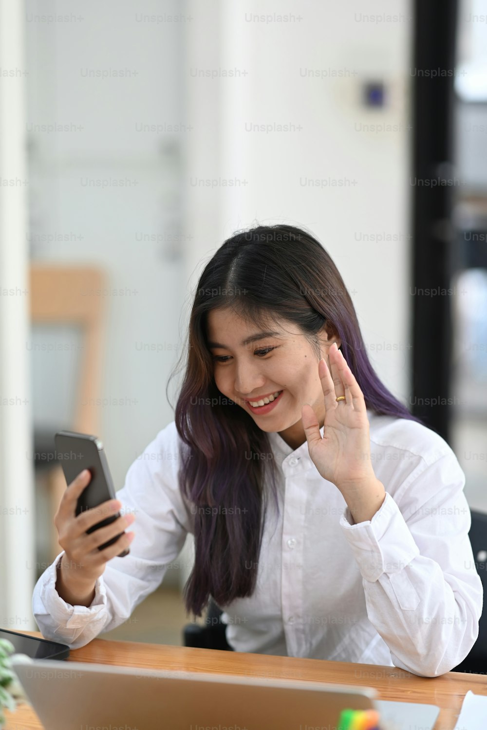 友人とスマートフォンでビデオ通話をしている陽気な若い女性。