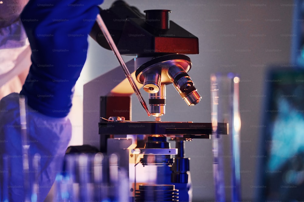 Scientist in white protective uniform works with coronavirus and blood tubes in laboratory.